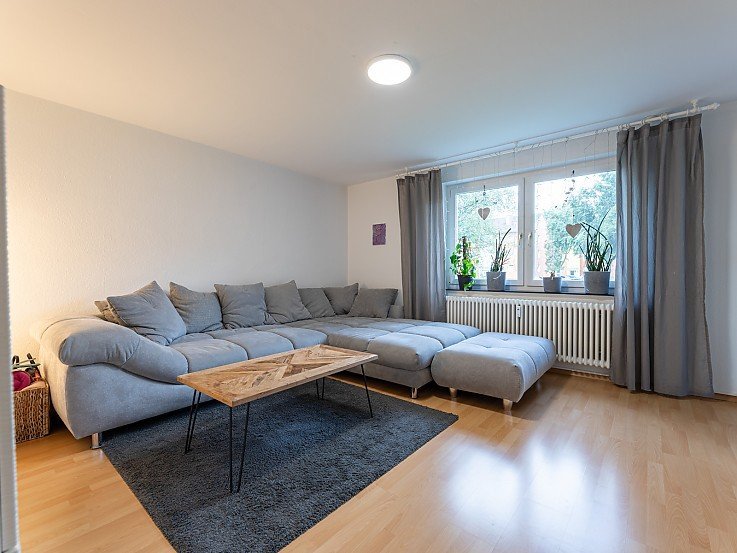 Helles Wohnzimmer mit Holzboden, grauer Couch und gro�em Fenster in Kaufbreuren - Wohnung erfolgreich verkauft durch Stockhausen Immobilienteam
