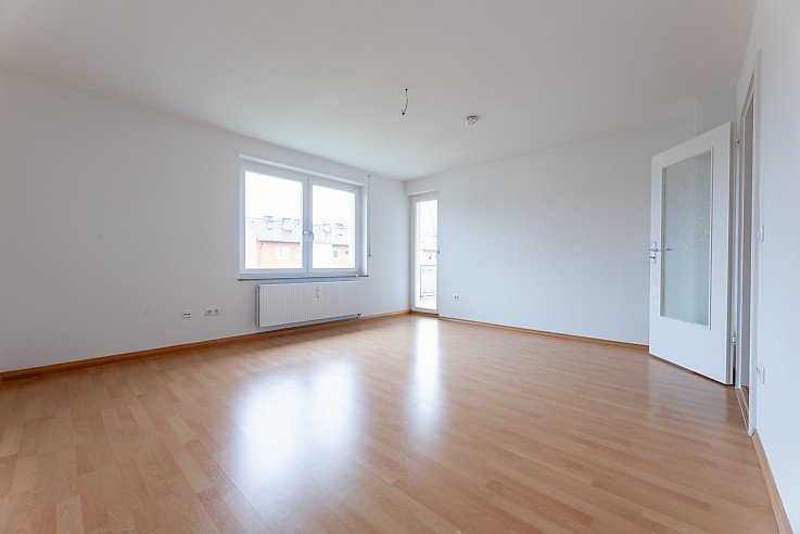 Helles leeres Wohnzimmer mit Holzboden und Balkonzugang in renovierter 3-Zimmer-Wohnung in Kaufbeuren - erfolgreich vermietet durch Stockhausen Immobilienteam