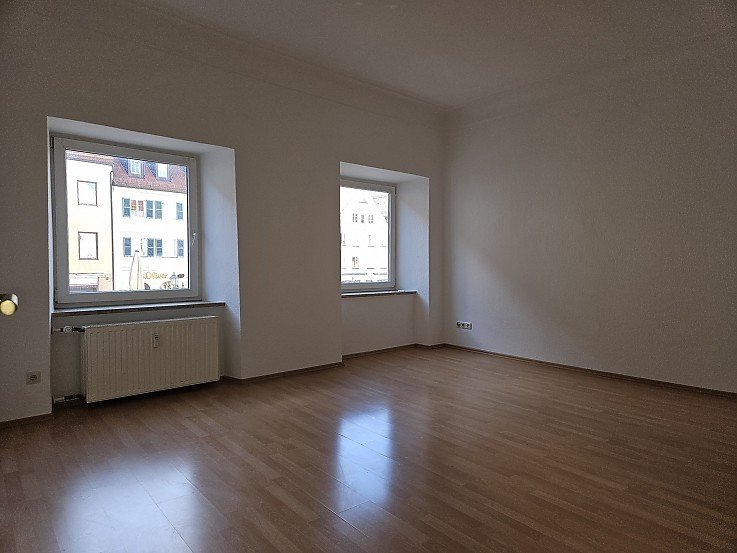 Helles leeres Wohnzimmer mit Holzboden und zwei Fenstern mit Blick auf die Schongauer Altstadt - 3-Zimer-Wohnung erfolgreich vermietet durch Stockhausen Immobilienteam