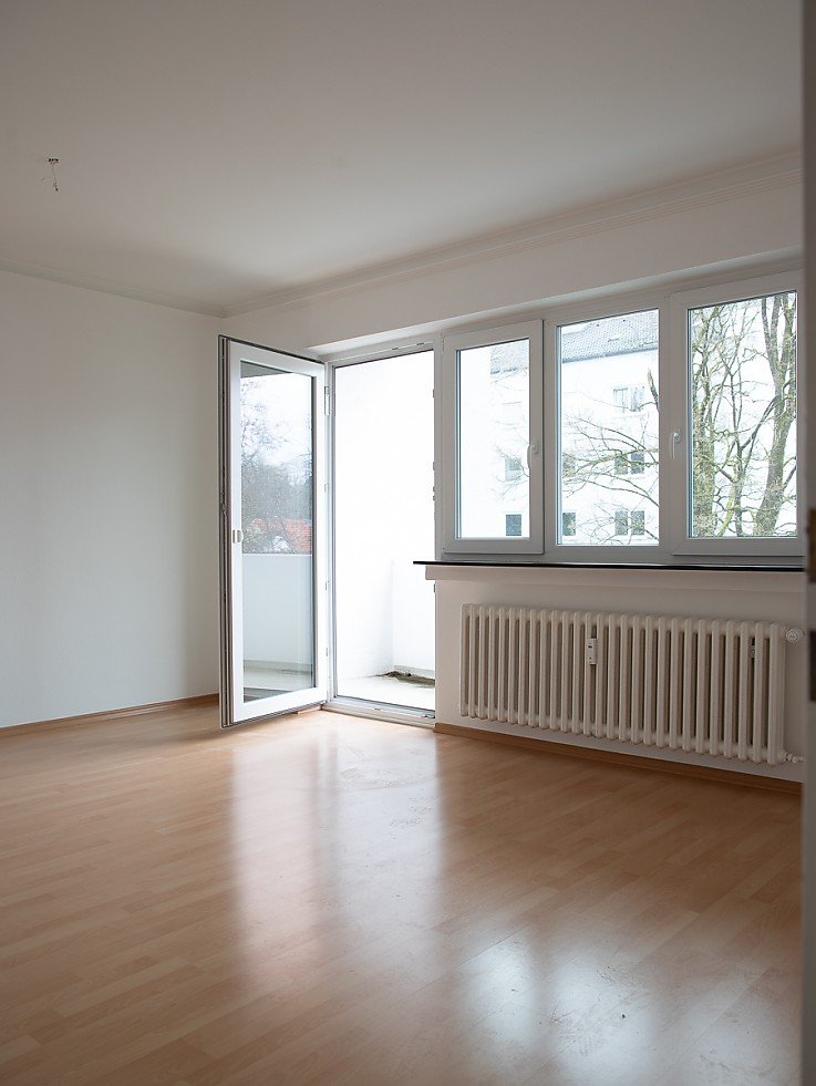 Helles leeres Wohnzimmer mit Holzboden, Balkonzugang und gro�er Fensterfront in 4-Zimmer-Wohnung in Schongau - erfolgreich vermietet durch Stockhausen Immobilienteam