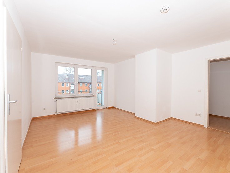Helles leeres Whhnzimmer mit Holzboden und Balkonzugang in 3-Zimmer-Wohnung in Kaufbeuren - erfolgreich verkauft durch Stockhausen Immobilienteam