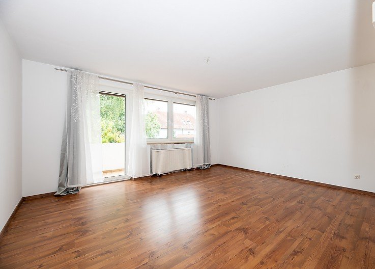 Helles leeres Wohnzimmer mit dunklem Holzboden, Balkonzugang und gro�en Fenstern in 3-Zimmer-Wohnung in Pei�enberg � erfolgreich verkauft durch Stockhausen Immobilienteam